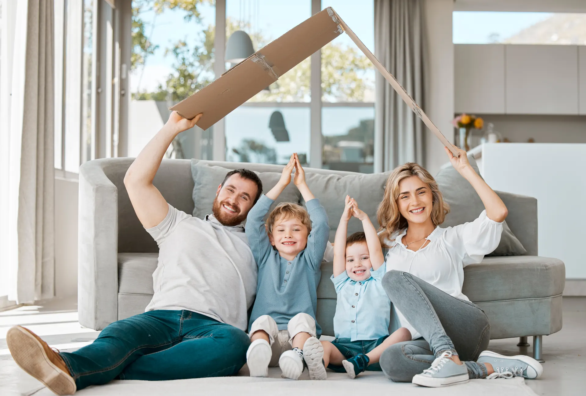 Familie freut sich im neuen Zuhause und formt mit Pappen ein Dach, Immobilienkauf und Verkauf mit Makler in der Weststadt Osnabrück